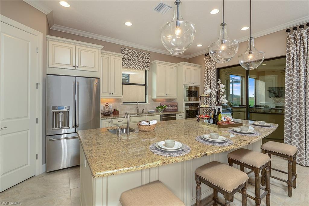 8558 Maggiore Court Naples, FL 34114 - Photo 12 of 32 a kitchen with stainless steel appliances granite countertop a dining table and chairs