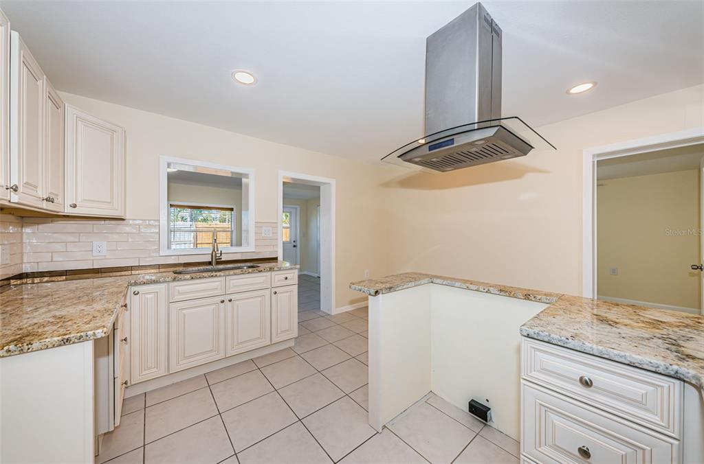 713 Pruitt Drive Madeira Beach, FL 33708 - Photo 12 of 62 a kitchen with granite countertop white cabinets and white appliances