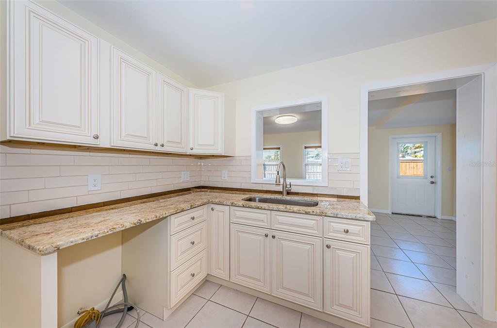 713 Pruitt Drive Madeira Beach, FL 33708 - Photo 13 of 62 a kitchen with granite countertop white cabinets white appliances and a sink