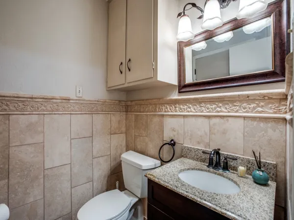 a bathroom with a granite countertop sink vanity mirror and toilet