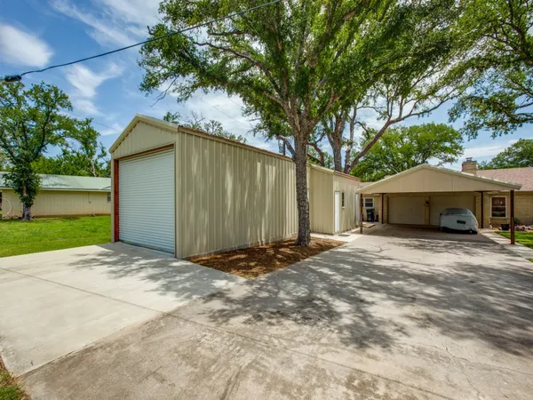 a front view of a house with a garden and trees