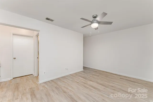 an empty room with wooden floor ceiling fan and window
