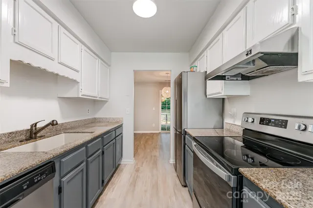 a kitchen with stainless steel appliances granite countertop a sink stove and cabinets