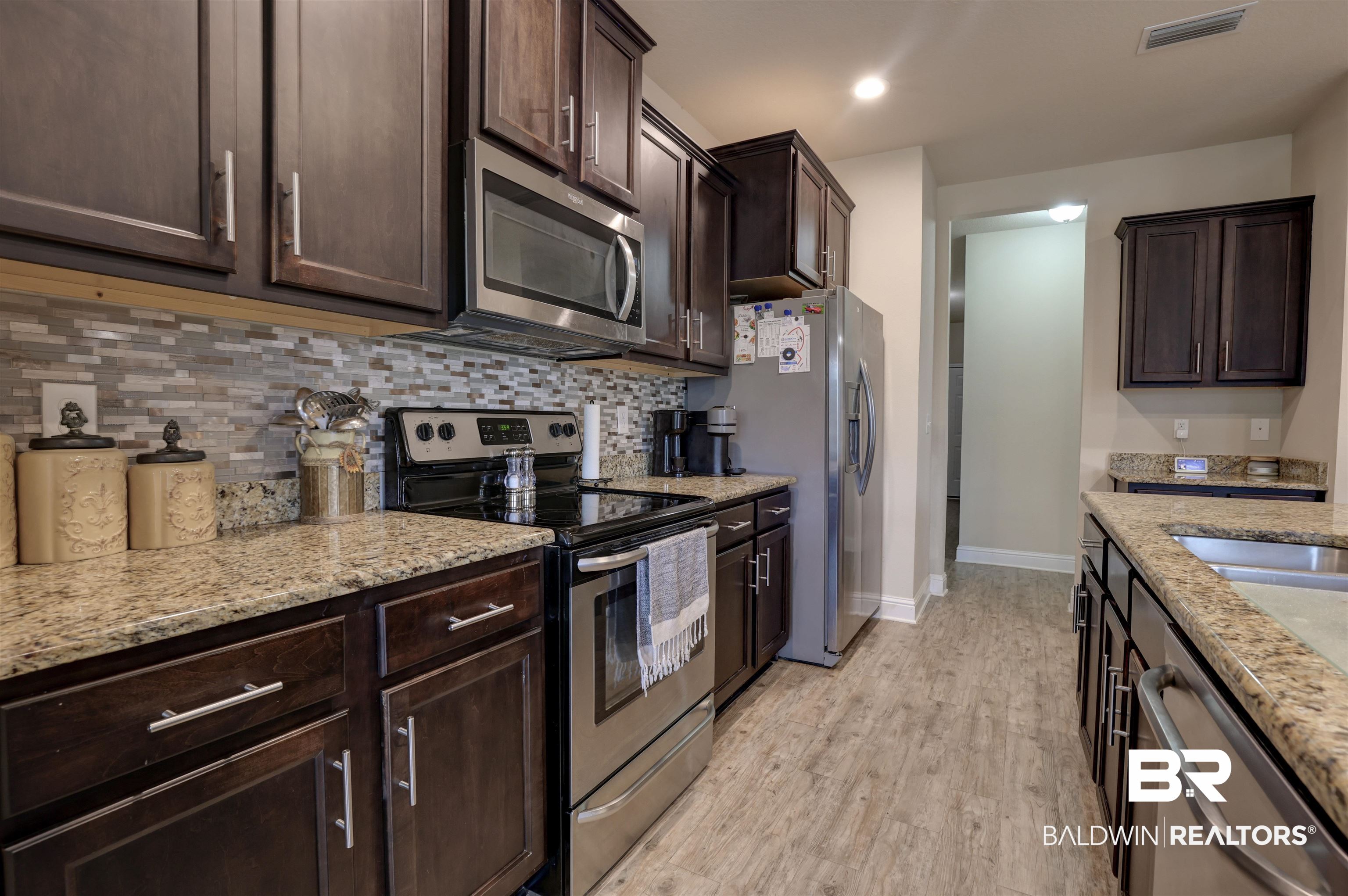 21902 Yosemite Boulevard Fairhope, AL 36532 - Photo 10 of 32 Kitchen with tasteful backsplash, light wood-type flooring, stainless steel appliances, and light stone counters