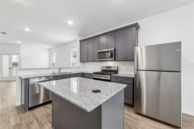 a kitchen with stainless steel appliances granite countertop a refrigerator a sink a stove a microwave and island