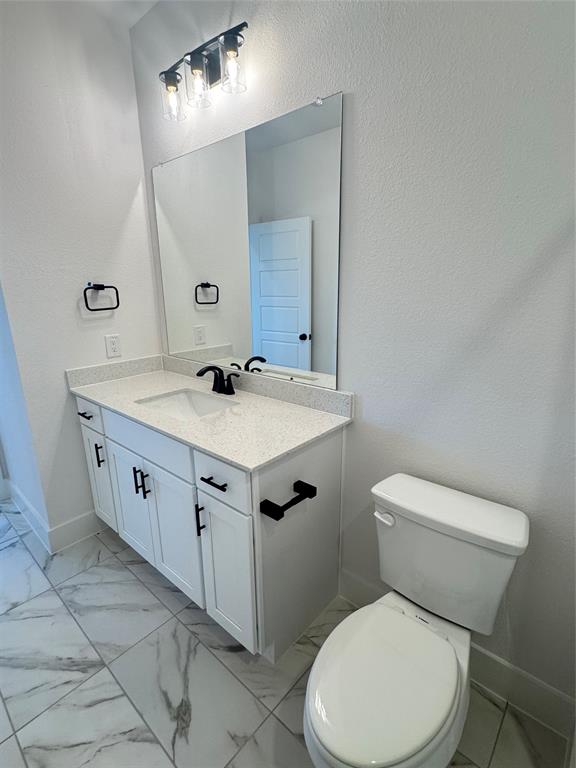 1313 Eureka Spgs Street Prosper, TX 75078 - Photo 25 of 40 Half bath with light marble finish floors, vanity, and a textured wall