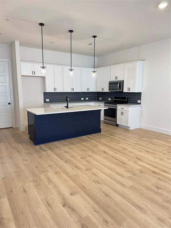 1313 Eureka Spgs Street Prosper, TX 75078 - Photo 27 of 40 Kitchen featuring white cabinetry, decorative light fixtures, an island with sink, range, and recessed lighting
