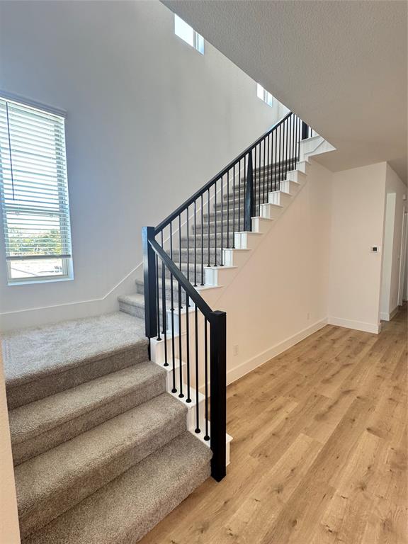 1313 Eureka Spgs Street Prosper, TX 75078 - Photo 35 of 40 Staircase featuring wood finished floors and a textured ceiling