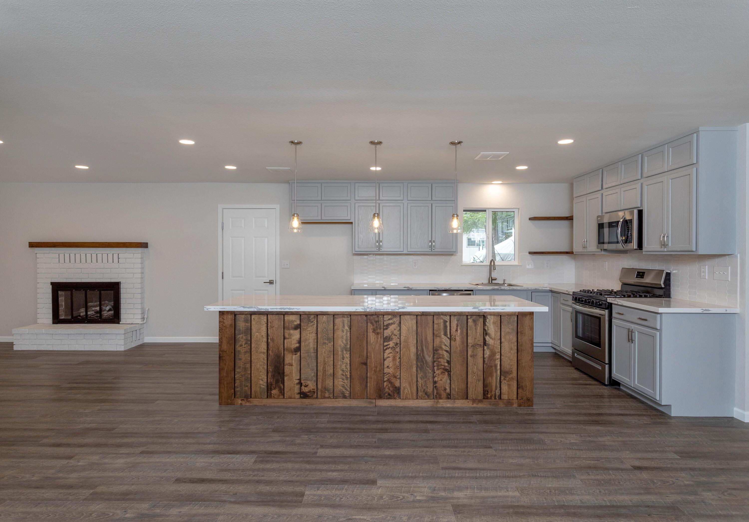 3693 Echo Road Redding, CA 96002 - Photo 5 of 30 a large kitchen with kitchen island a sink dishwasher a stove and a refrigerator with wooden floor