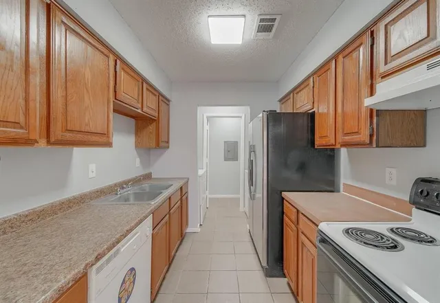 a kitchen with stainless steel appliances granite countertop a refrigerator a stove and a sink