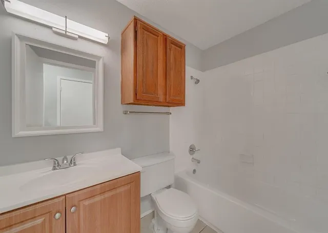 a bathroom with a granite countertop sink toilet and mirror