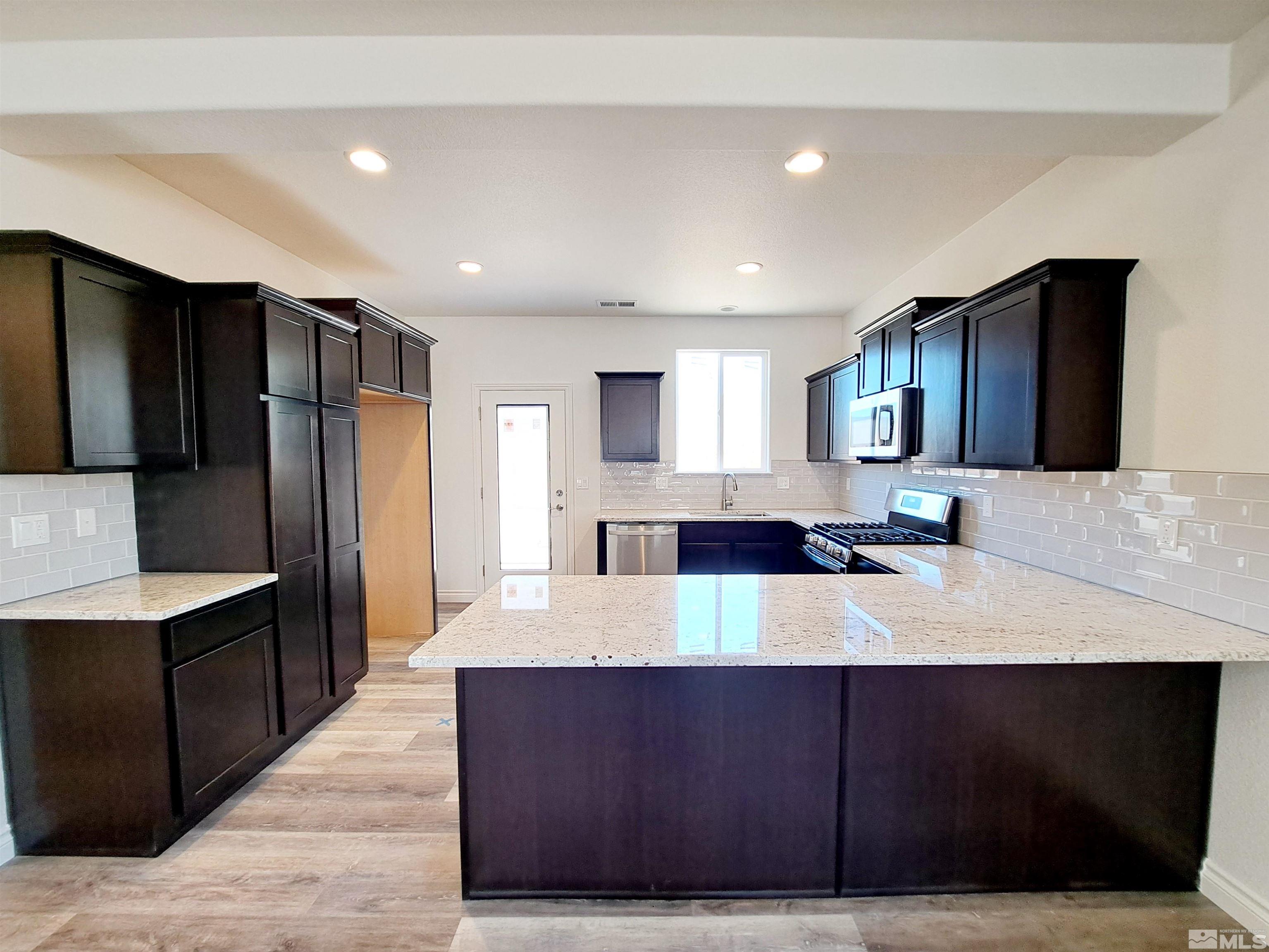19013 Alpine Walk Court, Unit LOT 1881 Reno, NV 89508 - Photo 3 of 26 a large kitchen with kitchen island granite countertop wooden cabinets a refrigerator and a sink