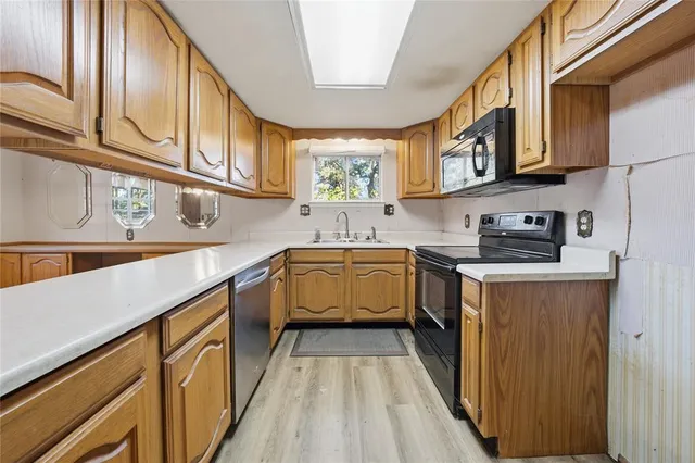 a kitchen with stainless steel appliances granite countertop a sink and dishwasher a stove top oven with wooden floor