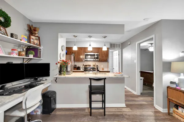 a view of kitchen with stainless steel appliances kitchen island granite countertop a sink and cabinets