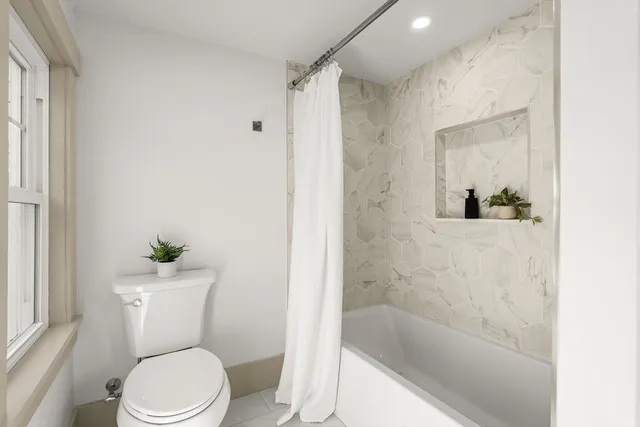 a white toilet sitting next to a bath tub