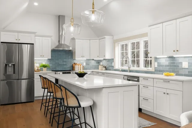 a kitchen with stainless steel appliances granite countertop a sink a stove a refrigerator and island with wooden floor