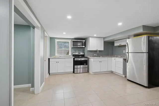 a kitchen with white cabinets and refrigerator