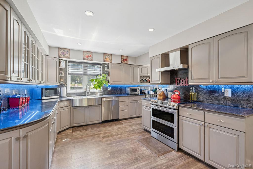 30 Lone Oak Path Smithtown, NY 11787 - Photo 8 of 39 a kitchen with stainless steel appliances granite countertop a stove top oven a sink dishwasher and cabinets with wooden floor