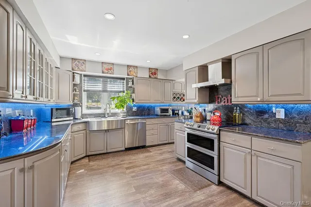 a kitchen with stainless steel appliances granite countertop a stove top oven a sink dishwasher and cabinets with wooden floor