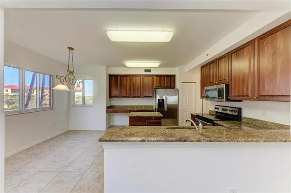 a kitchen with kitchen island granite countertop stainless steel appliances a stove refrigerator a sink a microwave oven with cabinets and wooden floor