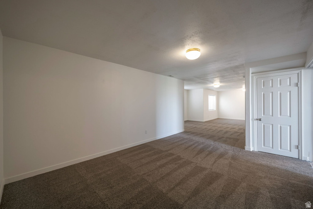 11922 Bluff View Drive Sandy, UT 84092 - Photo 19 of 30 Empty room featuring dark colored carpet and baseboards