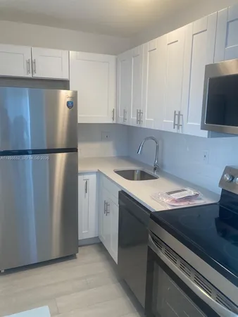 a kitchen with a sink a refrigerator and cabinets