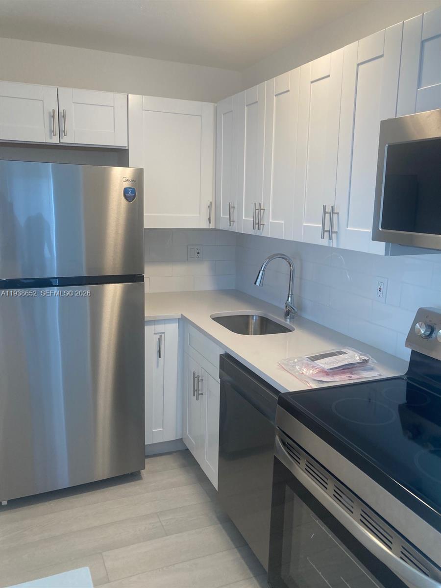 199 East McNab Road, Unit 101 Pompano Beach, FL 33060 - Photo 3 of 15 a kitchen with a sink a refrigerator and cabinets
