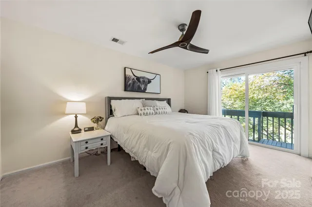 a bedroom with a bed a large window with table and chair