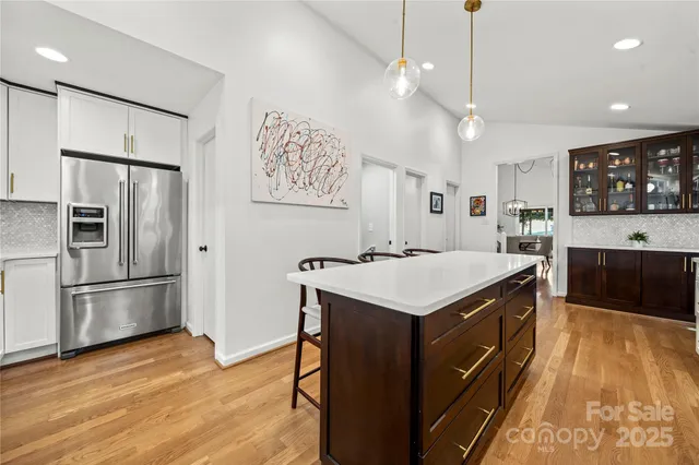 a kitchen with stainless steel appliances a sink a stove a refrigerator and island with wooden floor