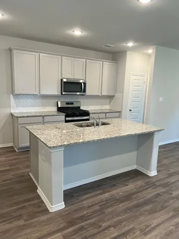 a kitchen with granite countertop a sink and a stove top oven