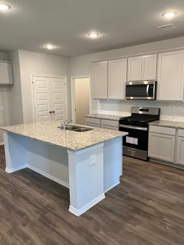 a kitchen with granite countertop a sink cabinets and wooden floor