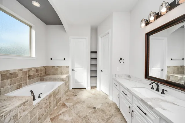a spacious bathroom with a tub sink and mirror