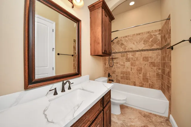 a bathroom with a granite countertop sink a toilet and bathtub