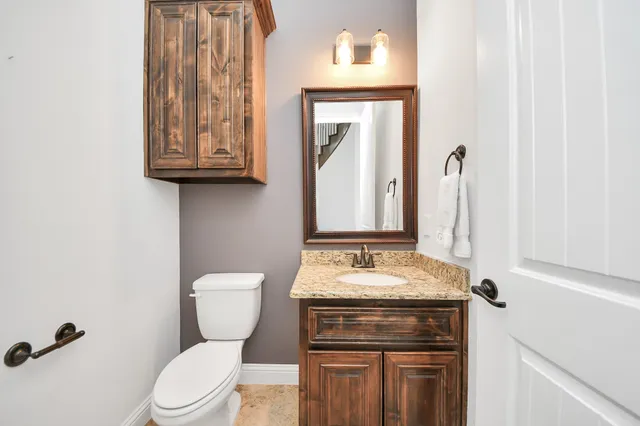 a bathroom with a granite countertop toilet sink and mirror