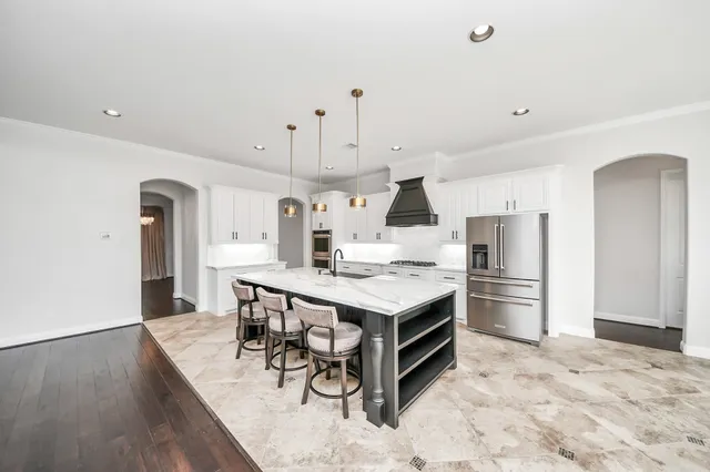 a kitchen with stainless steel appliances a stove a sink a refrigerator and a refrigerator with wooden floor