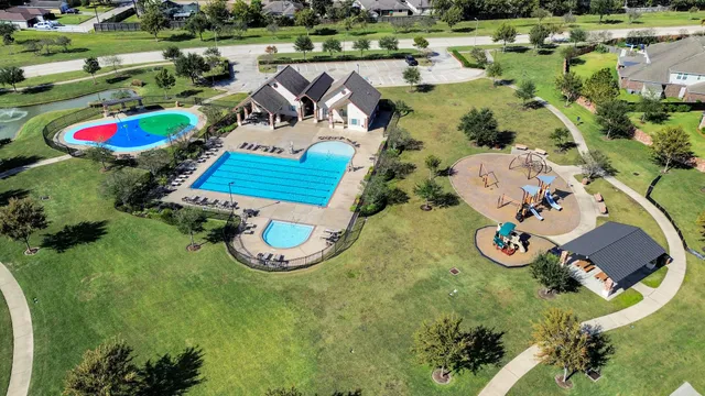 an aerial view of a house with swimming pool and large trees