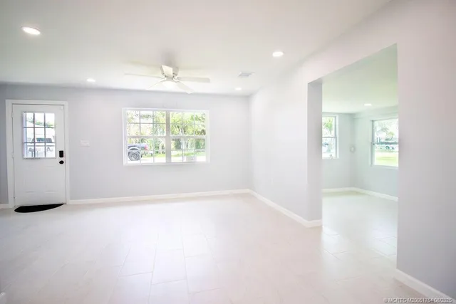 an empty room with windows and ceiling fan