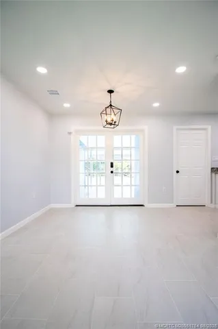 an empty room with chandelier fan and windows