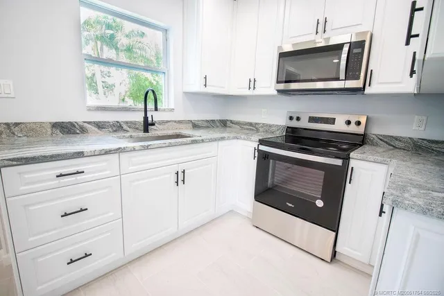 a kitchen with white cabinets appliances and a sink