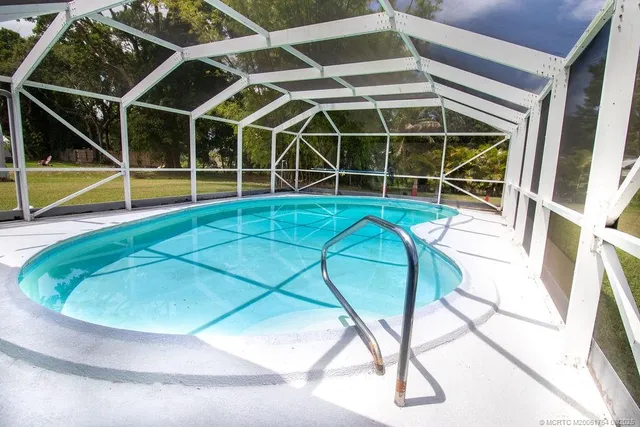 a view of a swimming pool with a yard and potted plants