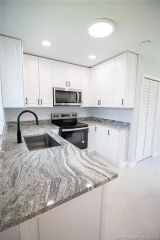 a kitchen with stainless steel appliances granite countertop a sink a stove and a refrigerator