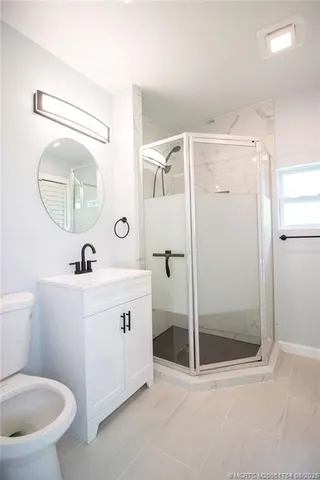 a bathroom with a toilet a sink a mirror and a shower