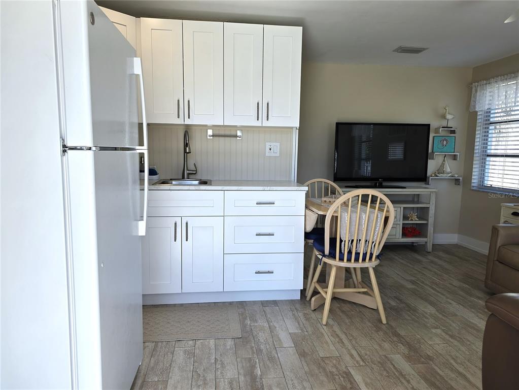 470 South McCall Road, Unit 11 Englewood, FL 34223 - Photo 8 of 22 a kitchen with a table chairs refrigerator and microwave