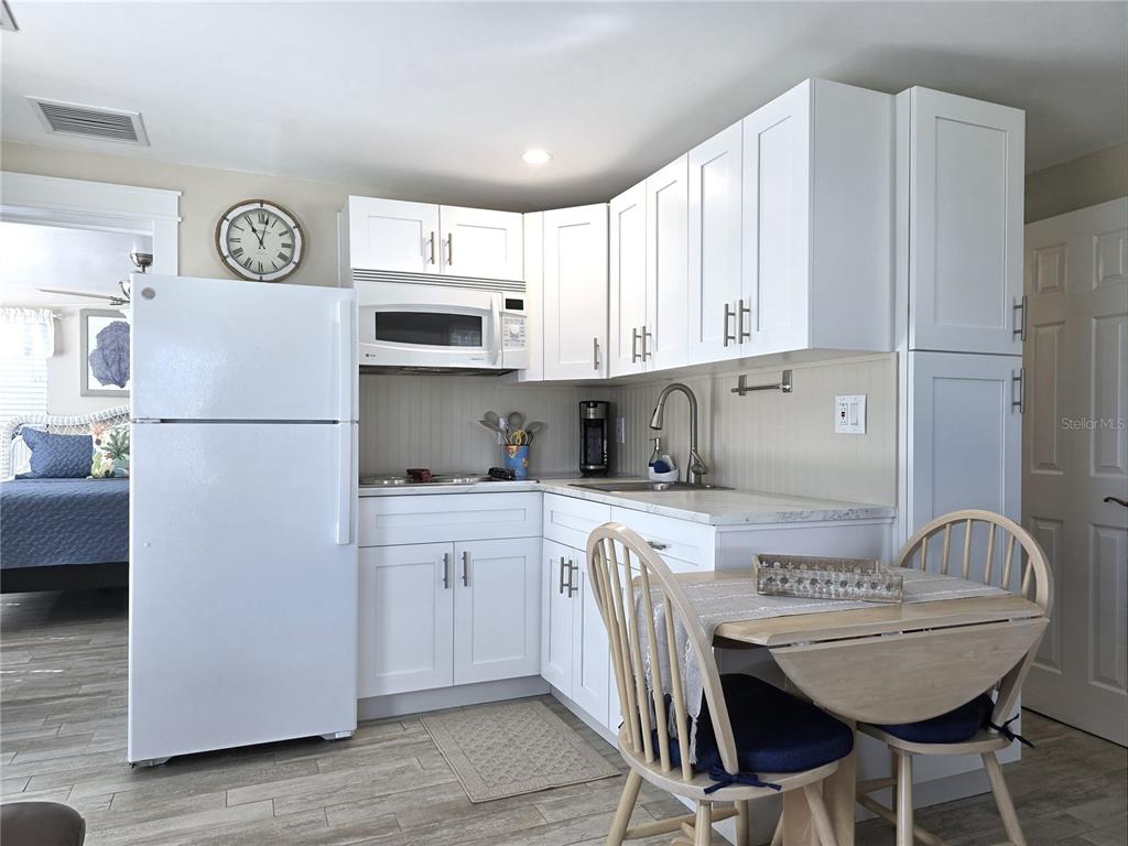 470 South McCall Road, Unit 11 Englewood, FL 34223 - Photo 10 of 22 a kitchen with stainless steel appliances granite countertop a refrigerator a stove a sink and white cabinets with wooden floor
