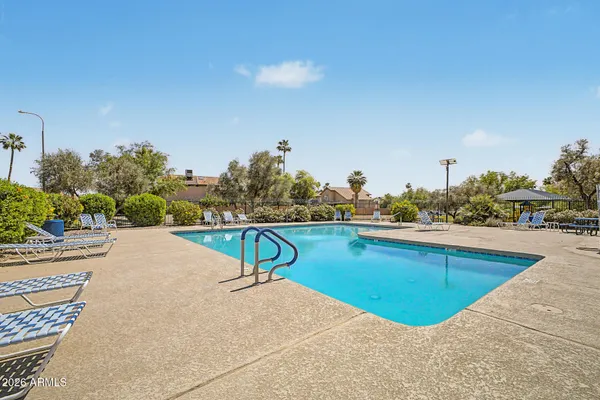 a bedroom with a bed a desk and chair with wooden floor