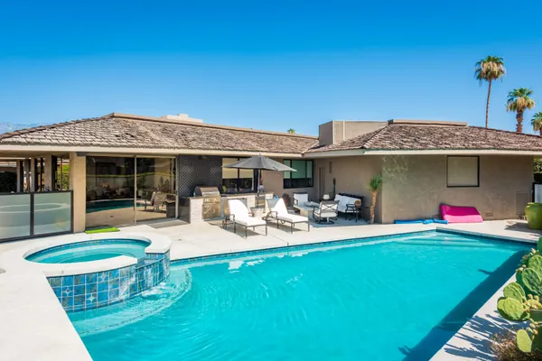 a front view of a house with swimming pool table and chairs