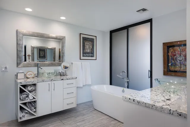 a bathroom with a granite countertop sink mirror and bathtub