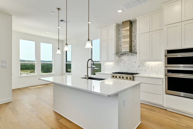 19005 Fernando Trail Austin, TX 78738 - Photo 4 of 26 White chef's kitchen with center island, quartz counters and luxury monogram 6 burners gas stove