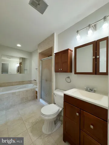 a spacious bathroom with a bathtub shower sink mirror and toilet