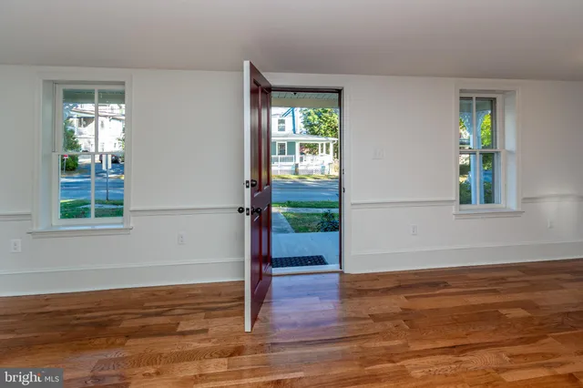 a view of an empty room with window wooden floor and front door